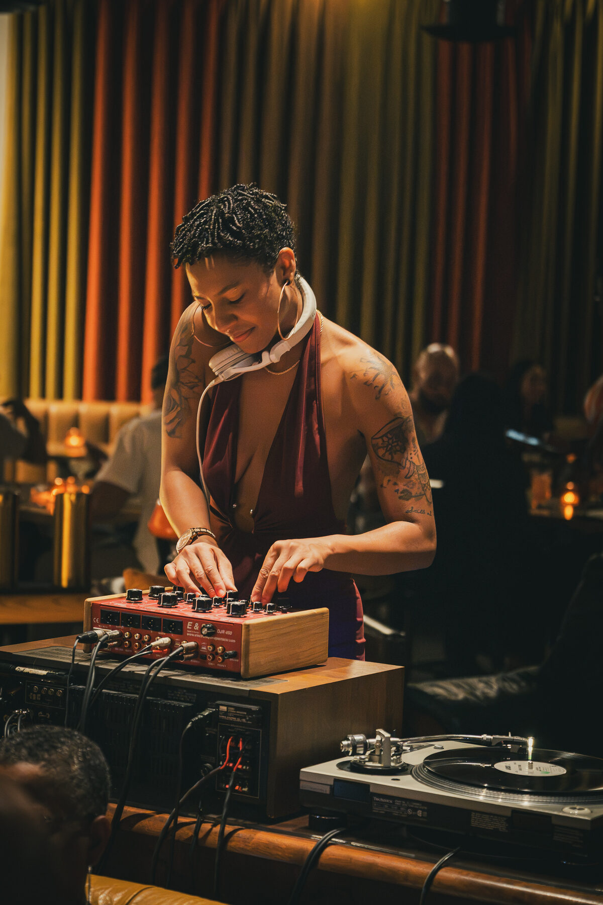 DJ Mahay adjusting a mixer at a warm-lit venue